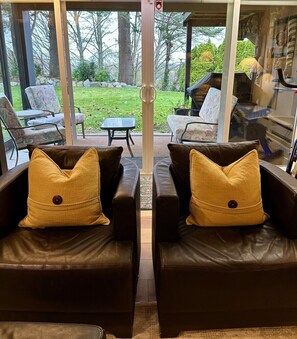 A room with two leather sofas facing a glass door leading to an outdoor patio area.