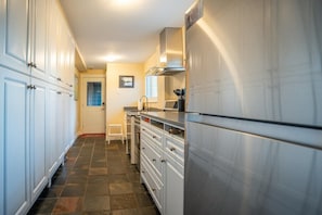 A kitchen with white cabinets, a stainless steel refrigerator, and a tiled floor.