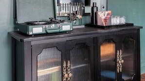 A black cabinet with a mirror above it, a record player, and various items on top. - Hollyhock Suite 302: 4 Bed/2 Bath (Louisville)