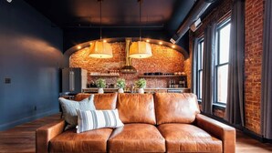 Ein modernes Wohnzimmer mit einem Ledersofa, einem Holztisch und einer Ziegelwand.