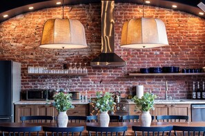 A restaurant with a brick wall, two hanging lamps, a bar area, and a dining table with chairs. - Hollyhock Suite 301: 4 Bed/2 Bath (Louisville)