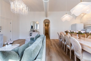 Un intérieur moderne avec un canapé, une table à manger, des chaises et un lustre.