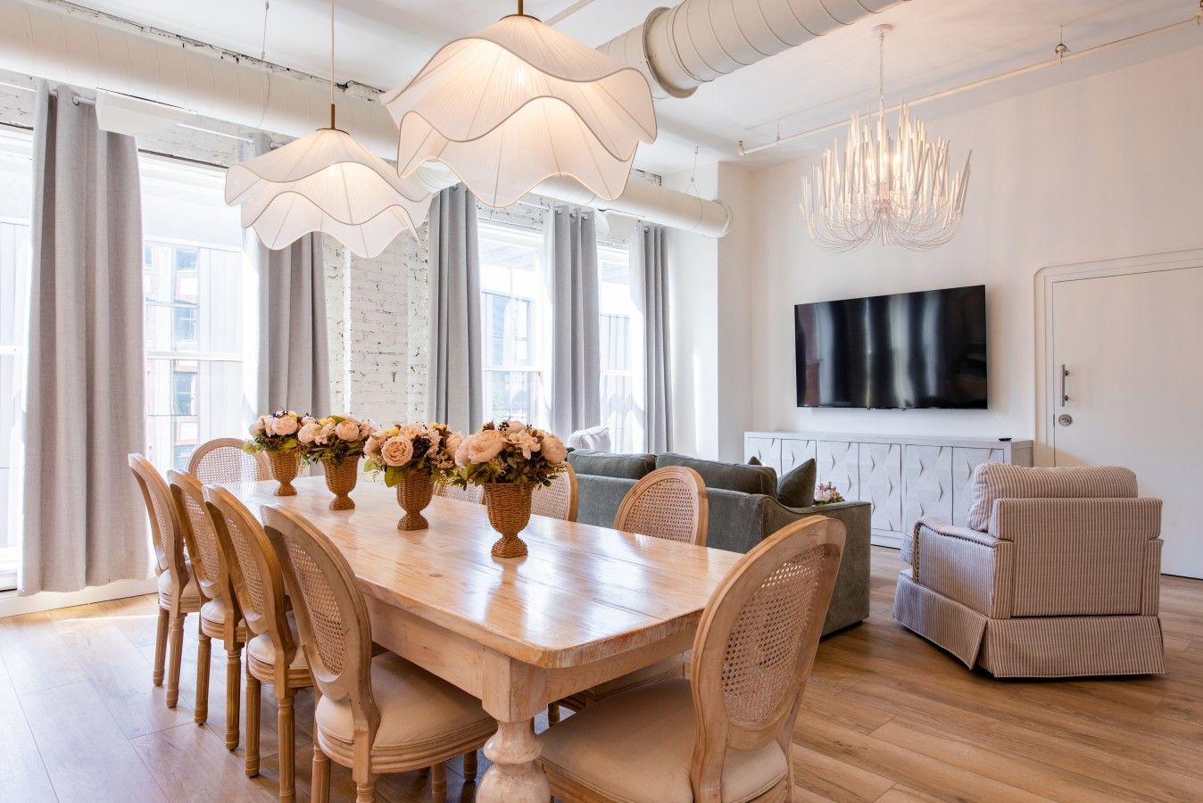Un coin repas avec une table en bois, des chaises en osier et un lustre.