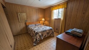 Une chambre avec un lit, une table de chevet avec une lampe, un miroir et une fenêtre avec des rideaux.