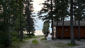 Un chemin de gravier mène à un chalet en bois qui offre une vue sur l’eau.