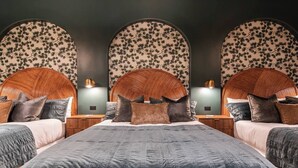 A hotel room with a large bed, two bedside tables, and a wall with a floral pattern. - Hollyhock Suite 304: 1 Bed/1 Bath (Louisville)