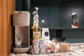 Eine Küchenzeile mit Kaffeemaschine, einer Flasche Monin French Vanilla Sirup und verschiedenen Gewürzen.