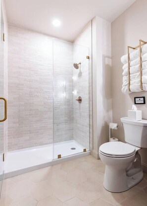 Ein modernes Badezimmer mit einer gläsernen Duschkabine, einer Toilette und einem Waschbecken mit Handtuchhalter.