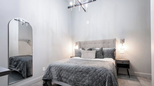 Una camera da letto moderna con un letto, comodini, uno specchio e un lampadario.