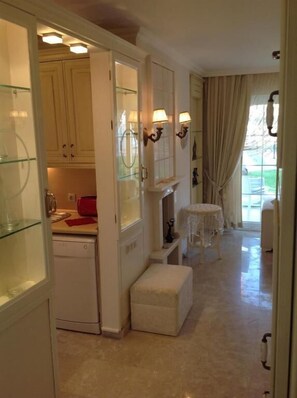A kitchen with a dishwasher, a small table, and a stool. There is a door leading to another room. - Villa B&D (Fethiye)