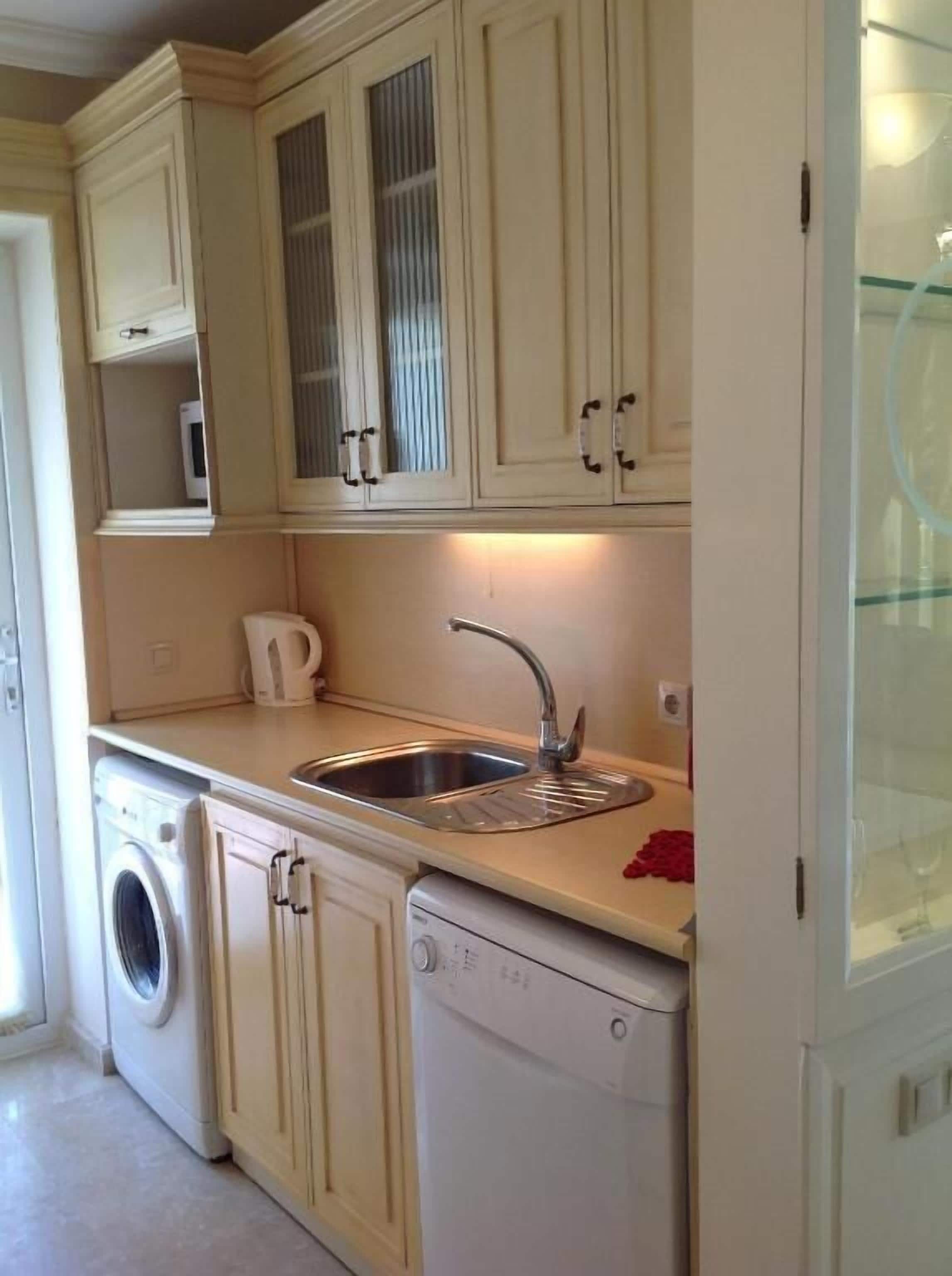 A compact kitchen with a washing machine, dishwasher, and a microwave.