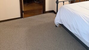 Un dormitorio con una cama, una puerta de madera y piso alfombrado.