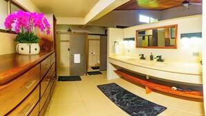Ein modernes Badezimmer mit einem Holzkosmetikschrank, einem großen Spiegel und einer Topfpflanze Orchidee.