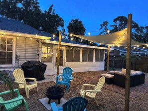 A backyard patio with outdoor furniture, a fire pit, and string lights. - Coastal Charm, Chic Home Near The Beach! (Port Orange)