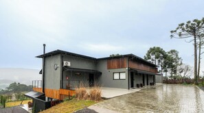 A modern two-story building with a flat roof, a covered outdoor area, and a paved driveway.