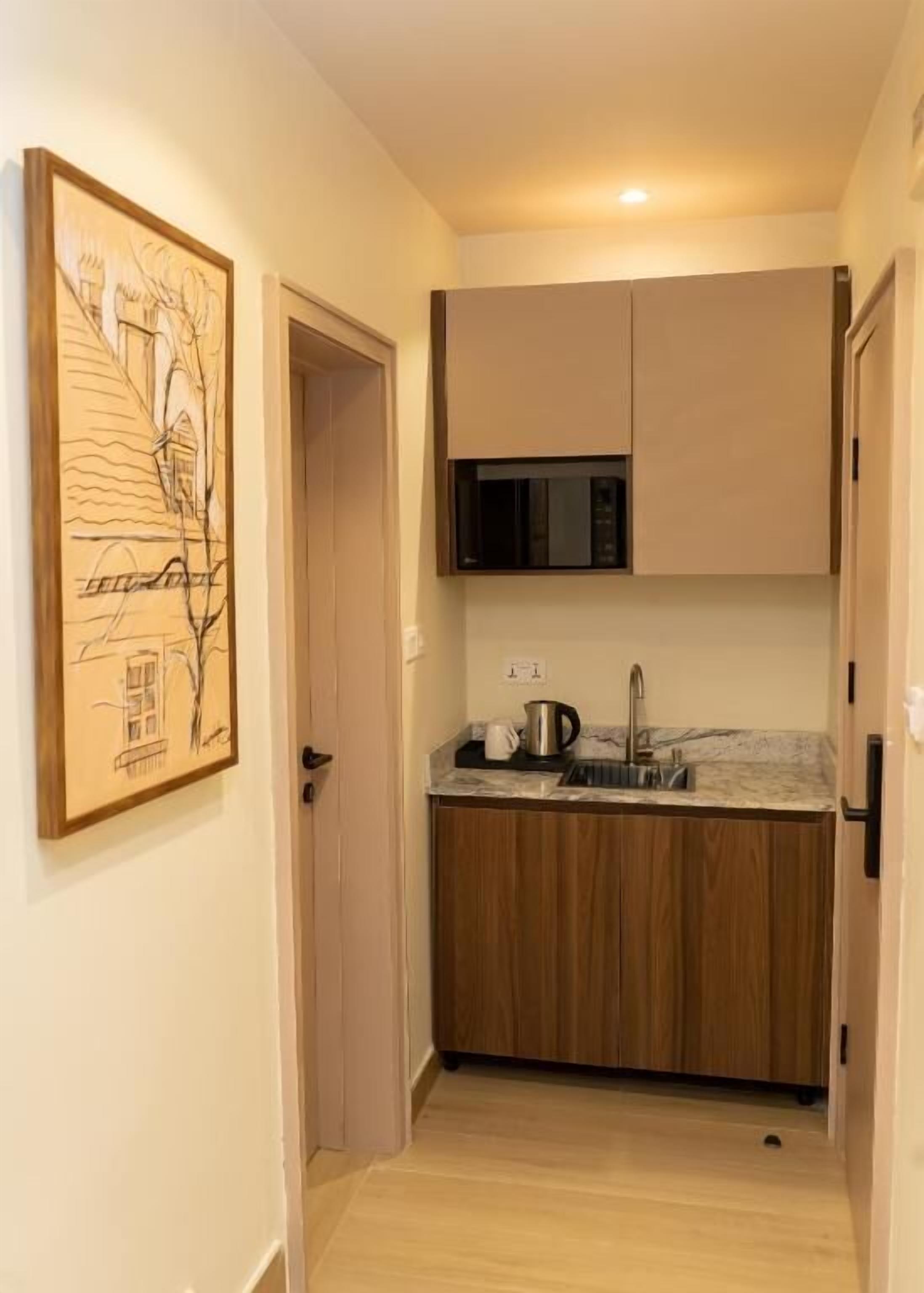 Una cocina compacta con muebles de madera, un microondas y un lavamanos.