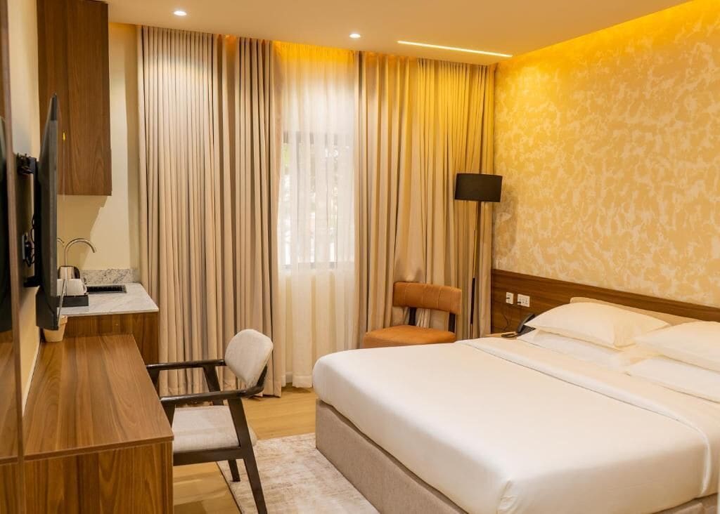 Una camera d'albergo con un letto, una scrivania, una sedia, una televisione e una lampada.
