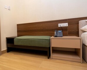 A hotel room with a wooden headboard, a bedside table with a telephone, and a green bedspread. - 7EVEN Suites (Lagos)