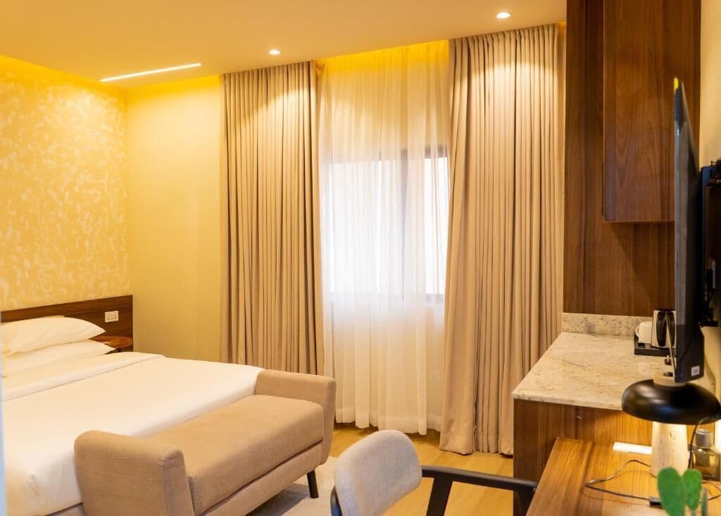 A hotel room with a bed, a desk, and a television.