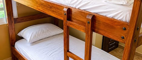 A bunk bed with a wooden frame and white bedding.