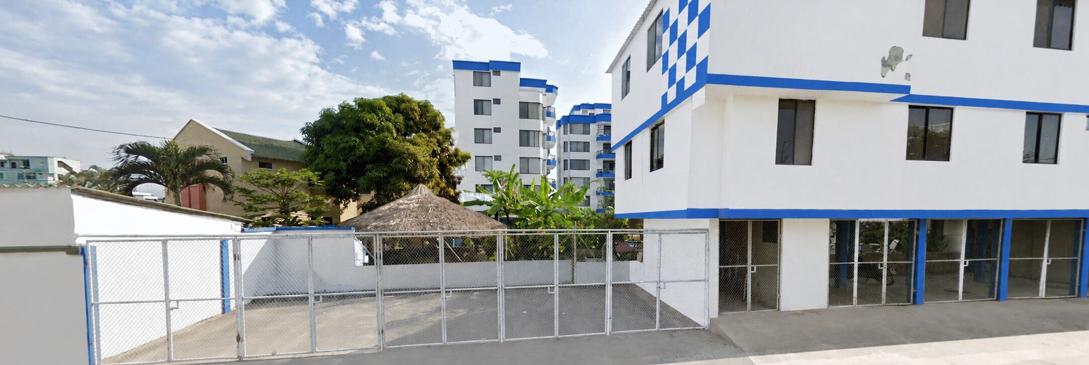 A modern building with multiple floors, a gated entrance, and a clear sky.