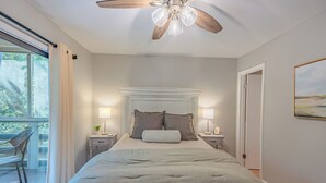 Una camera da letto con un letto, due comodini, una ventola a soffitto e una finestra con tende.