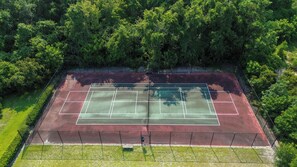 An aerial view of a tennis court surrounded by dense greenery. - Amelia Island Condo - secret walking trail to the beach! (Fernandina)