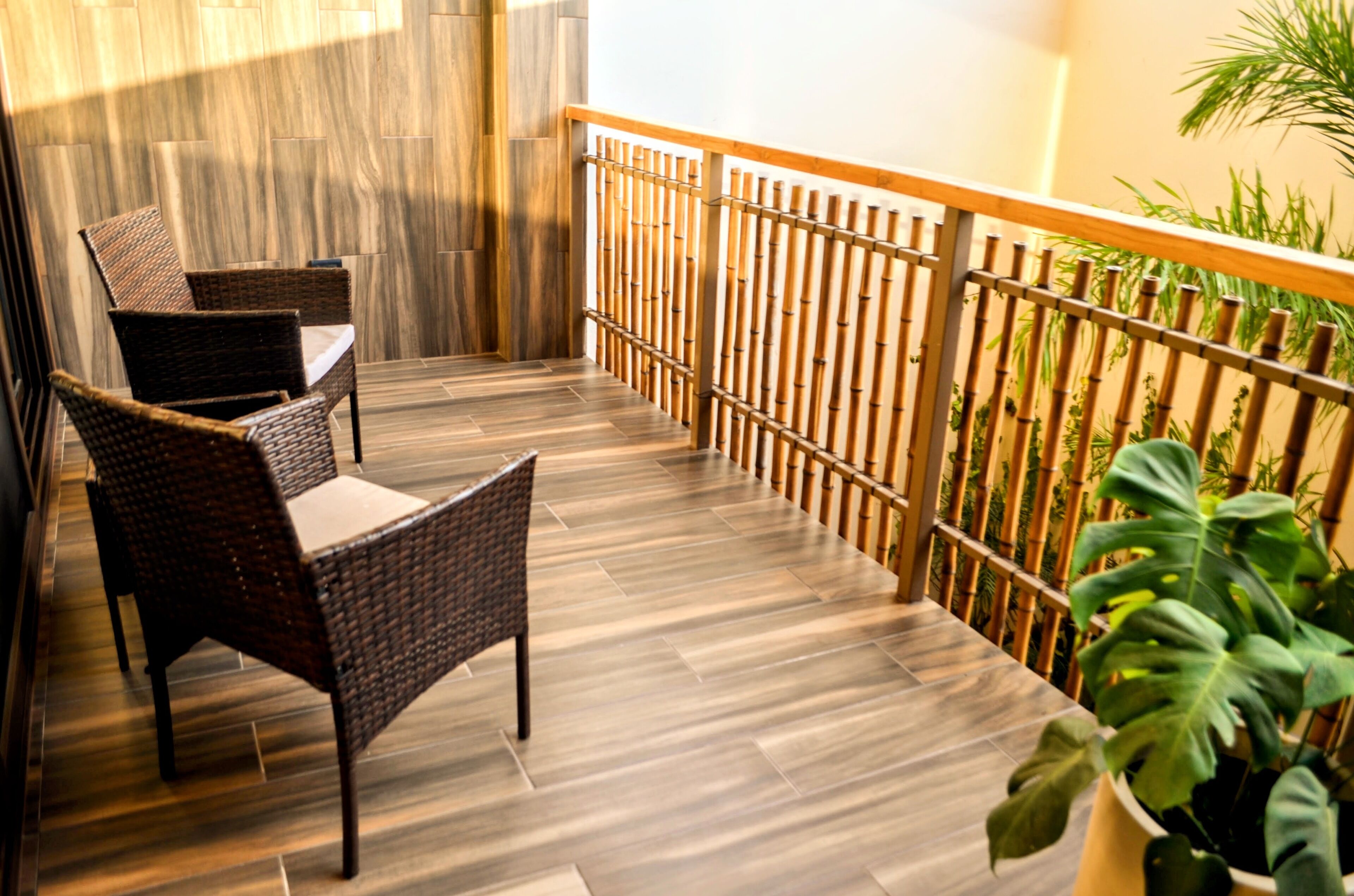 Een balkon met rieten meubilair en een houten vloer.