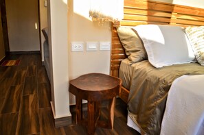 A bedroom with a wooden headboard, a small wooden stool, and a bed with a beige and white bedding.