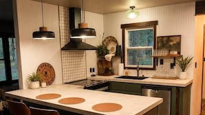 Cozinha moderna com uma ilha grande, banquetas, iluminação pendente e vista para o exterior.