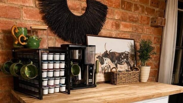 Uma bancada de cozinha com armários embutidos, uma decoração de parede preta suspensa e diversos utensílios de cozinha.