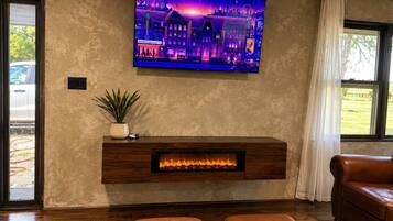 A living room with a fireplace, a television mounted on the wall, and a leather sofa.