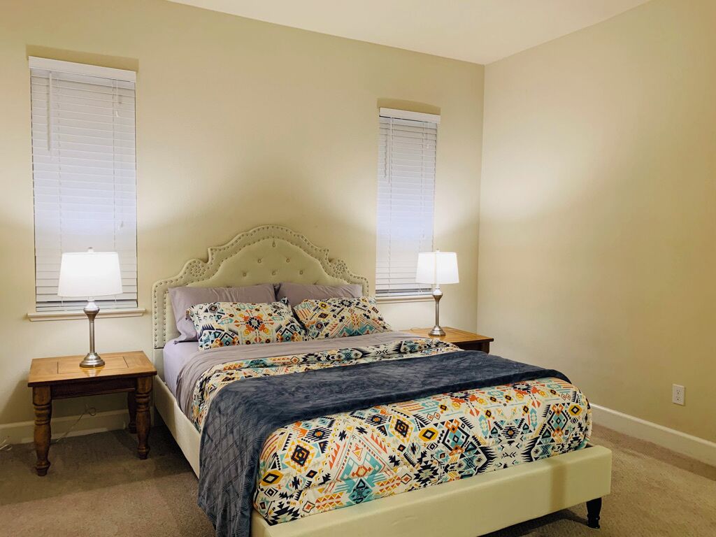 A bedroom with a bed, two bedside tables, and two lamps.