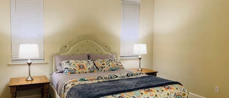 A bedroom with a bed, two bedside tables, and two lamps.