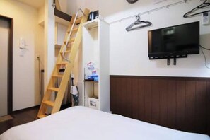 A hotel room with a bed, a television mounted on the wall, a wooden ladder, and a closet with shelves. - Near the station / Quiet area / Shinjuku center / Room 203 (Shinjuku City)
