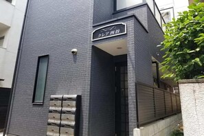 Ein Gebäude mit dunkler Backsteinfassade, einem Schild mit japanischen Schriftzeichen und einem verschlossenen Eingang.
