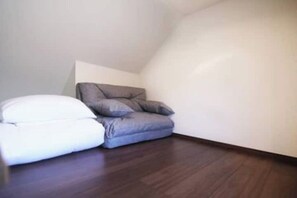 A corner room with a dark wooden floor, a white pillow, and a grey cushion. - Near the station / Quiet area / Shinjuku center / Room 203 (Shinjuku City)