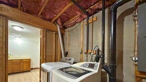 Ein Waschraum mit Waschmaschine, Trockner und sichtbarer Sanitärinstallation.