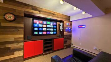 Een kamer met een wandgemonteerde televisie waarop verschillende streaming-apps worden weergegeven, een neonbord en een klok aan de muur.