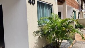 A modern building with a flat facade, a visible number '40', and a small garden area with palm trees. - Casa 40, Condomínio Lençóis Ville Residence (Barreirinhas)