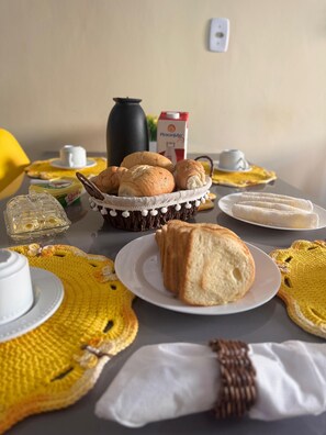 Ein Tisch mit verschiedenen Speisen, darunter Brot, ein Korb und ein Teller mit einer weißen Stoffserviette.