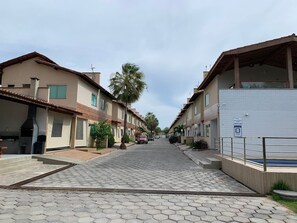 Rua residencial com casas, um calçada pavimentada e uma piscina.