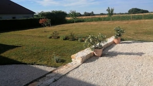 A residential property with a gravel driveway, a grassy yard, and a house with a sloped roof.