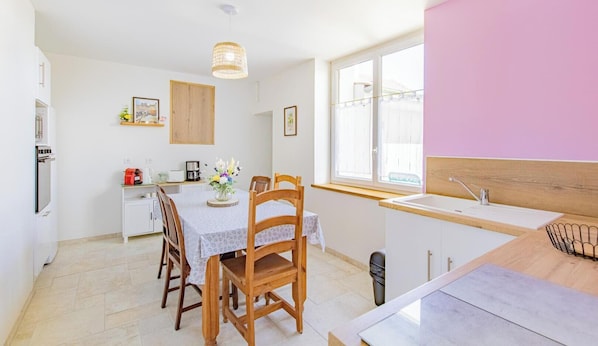 Una cocina moderna con comedor, que incluye una mesa de madera, sillas y una lámpara colgante.