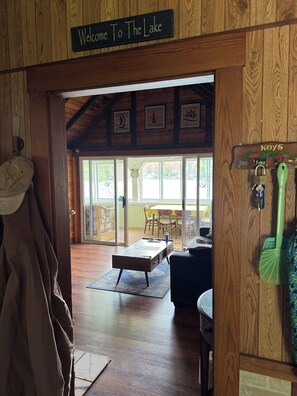 A wooden interior with a welcome sign, a dining area with a table and chairs, and a coat rack with keys. - China Lake Waterfront Getaway at relaxing Camp Loonsong (China)