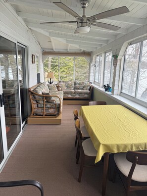 A sunroom with a sofa, chairs, a table, and a ceiling fan.