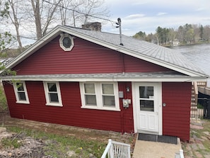 A red single-story house with a white door and windows, a small porch, and a chimney.