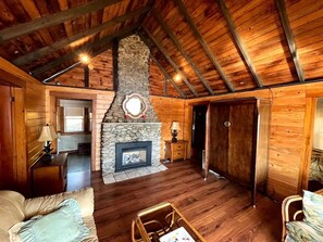 A rustic cabin interior with a stone fireplace, wooden walls, and a high ceiling. - China Lake Waterfront Getaway at relaxing Camp Loonsong (China)