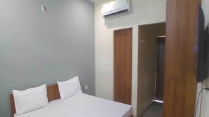 Ein Schlafzimmer mit Bett, Nachttisch, Klimaanlage und Kleiderschrank.