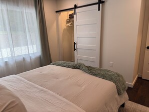 Une chambre à coucher avec un lit, un placard à porte coulissante et une fenêtre avec des rideaux.